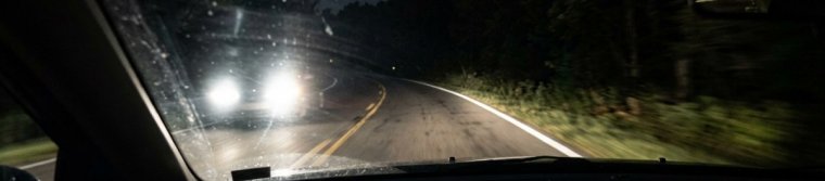 View from a car at night: oncoming headlights on the left and a bright white edge line on the right side of the lane
